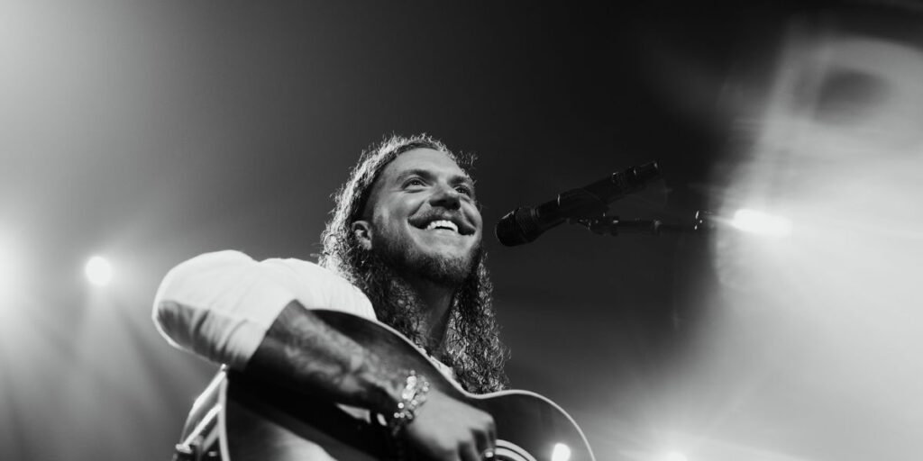 Brandon Lake performing live at a 2025 concert with fans cheering in the arena.
