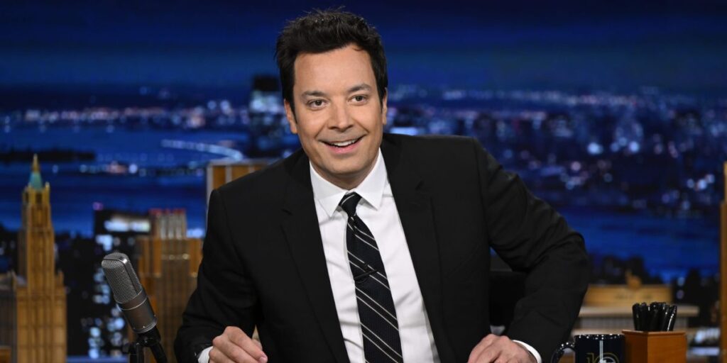Jimmy Fallon hosting The Tonight Show in 2025, wearing a suit and engaging with the audience