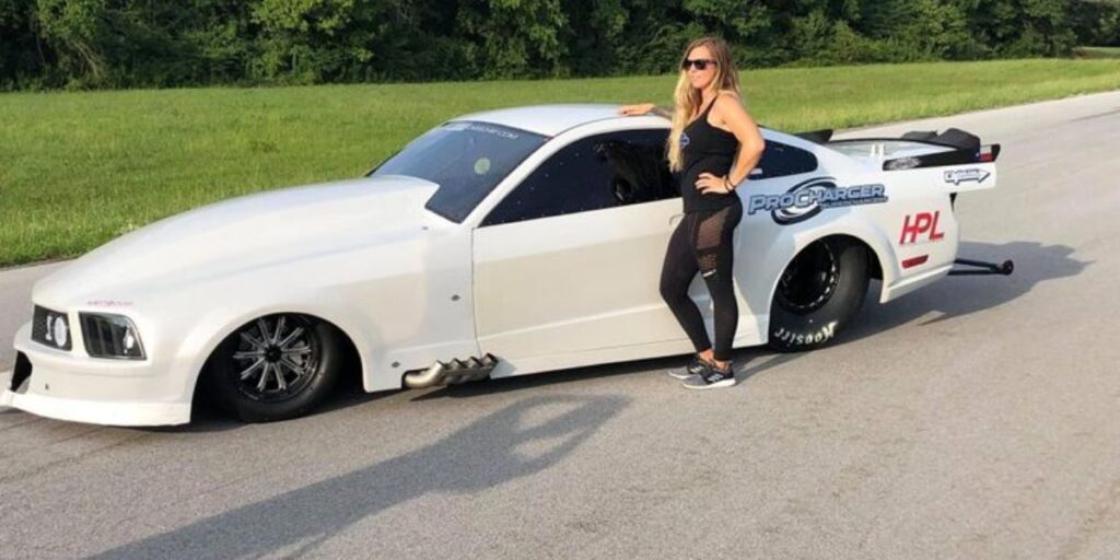 Kayla Morton posing with a “Hot Mess Express” graphic, showcasing her bold racing personality and strong presence in the drag racing community.

